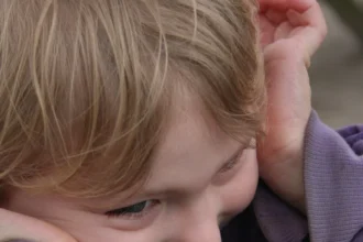 Child with autism covering their ears due to sensory sensitivity, a common reaction to overwhelming stimuli.