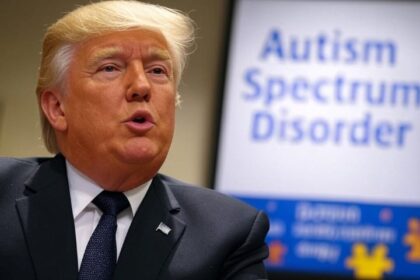 Donald Trump speaking in front of a sign that reads "Autism Spectrum Disorder" with puzzle piece graphics in the background.